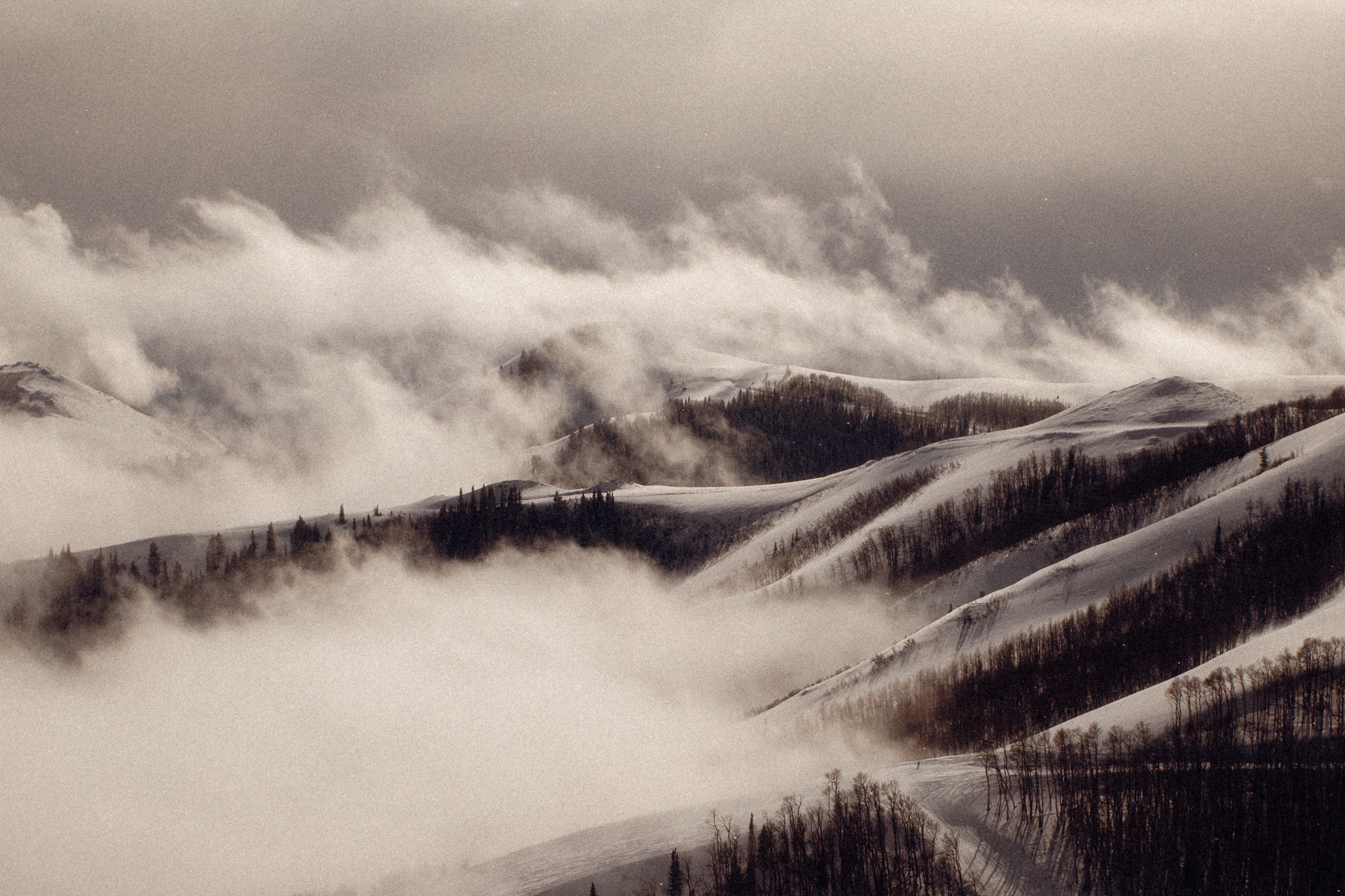 Fog rolling through snow-covered mountains