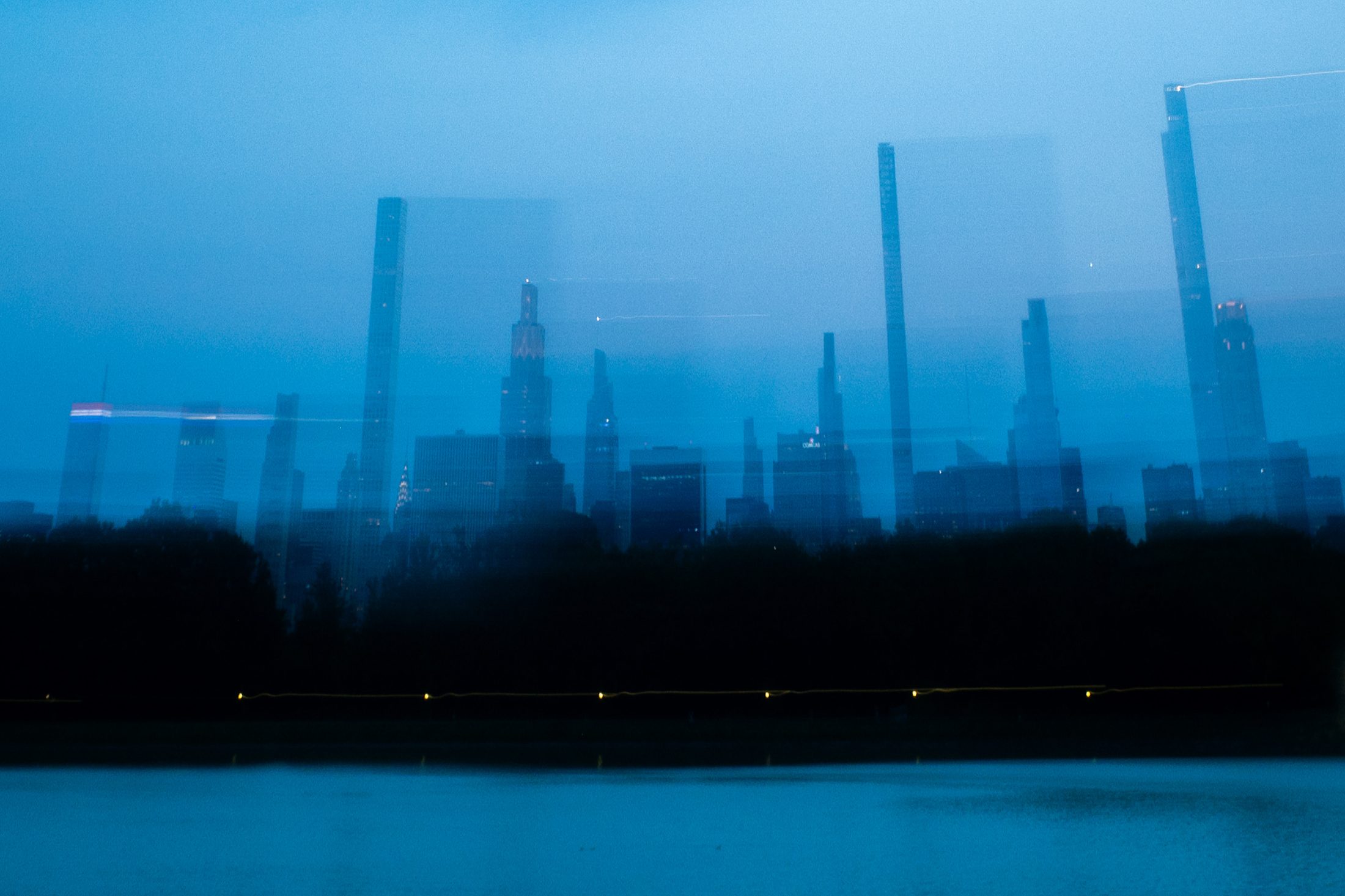 Double-exposure Manhattan skyline at dusk over Central Park