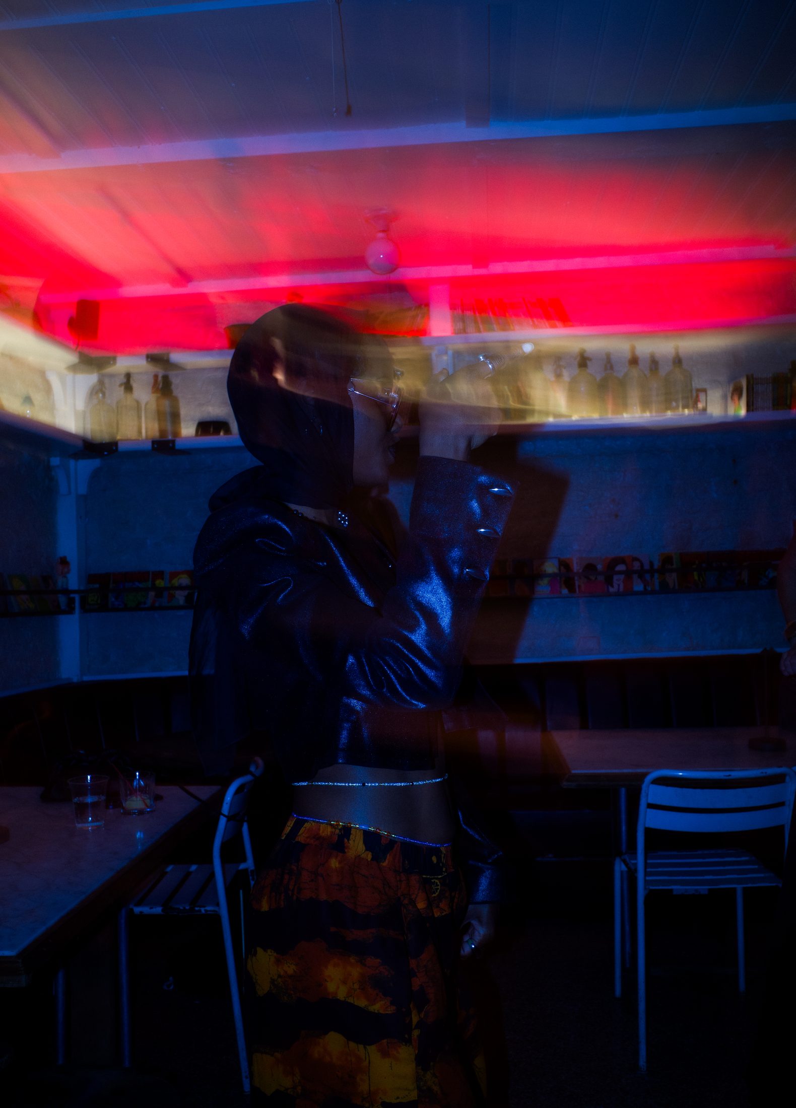 Double-exposure portrait at a bar, red and blue light